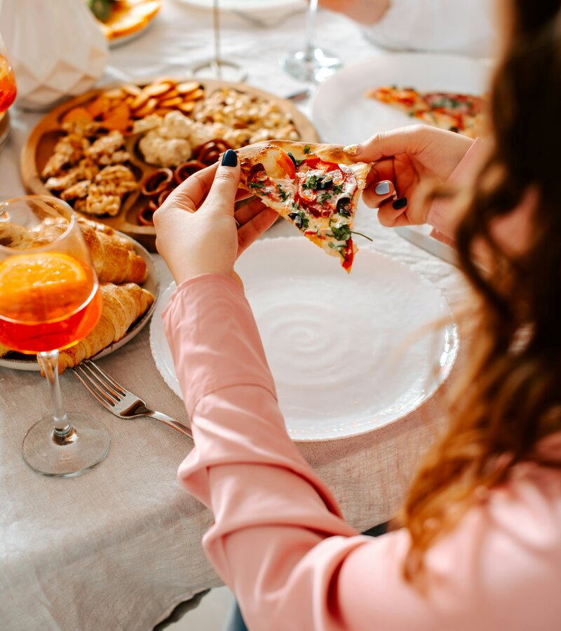 Eine Frau isst ein Stück Pizza an einem Tisch