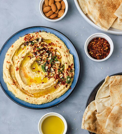 Ein Teller mit Hummus, Faldenbrot und eine Schüssel Olivenöl
