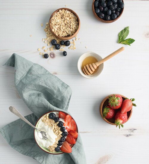 Schüssel Joghurt mit Beeren und Haferflocken auf dem Tisch