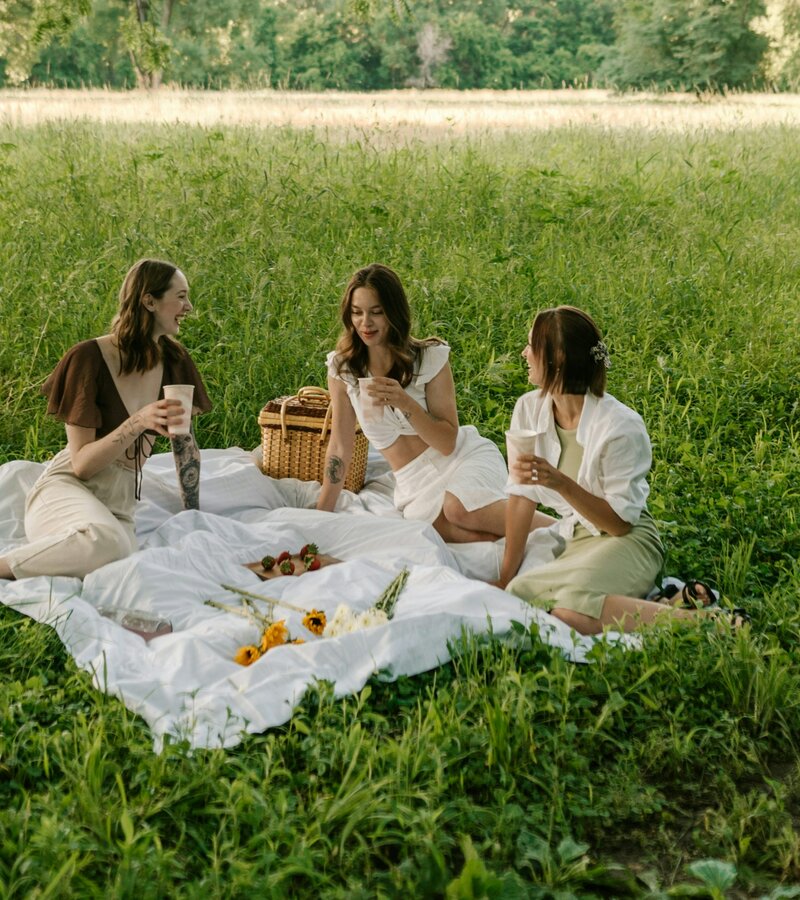 Eine Gruppe von Frauen, die auf einer üppigen grünen Wiese sitzen